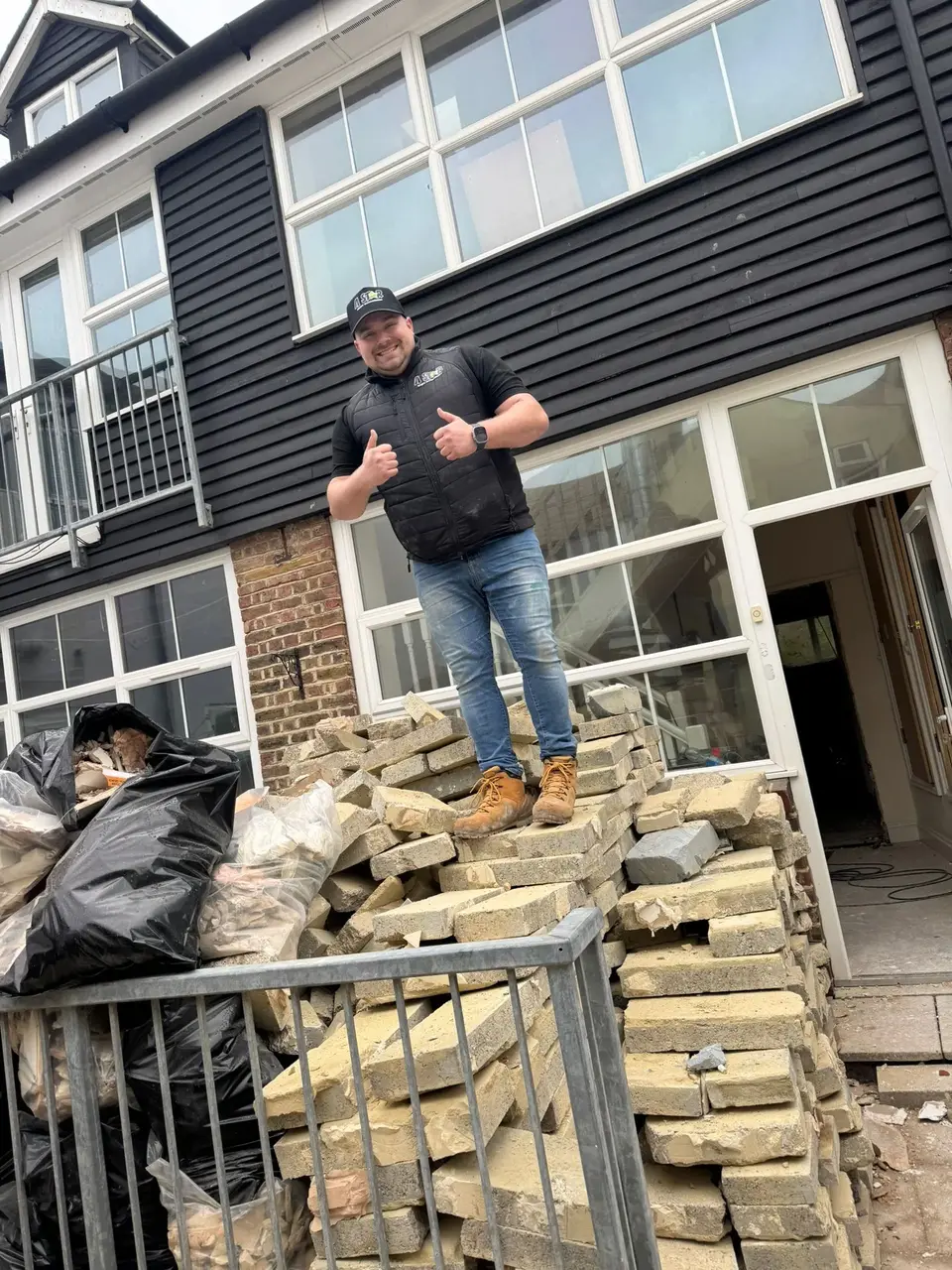 Jordan giving a thumbs up beside bagged waste and bricks on a clearance job