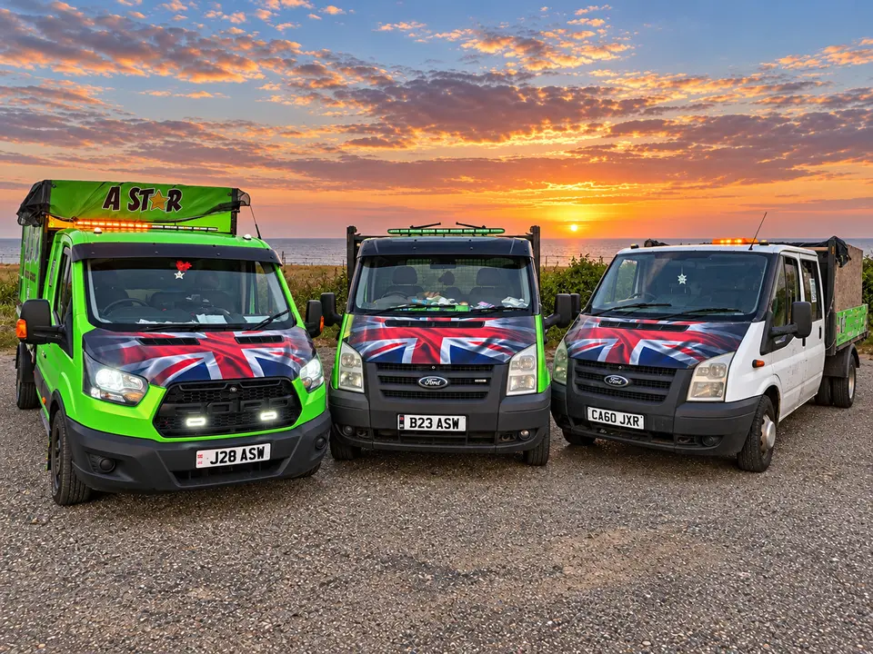 The A Star Waste Management fleet at sunset on the Sussex coast: three tipper vans with Union Jack bonnets