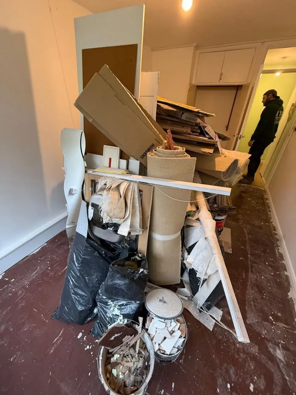 Interior strip-out in progress with old fittings and bags piled in a hallway