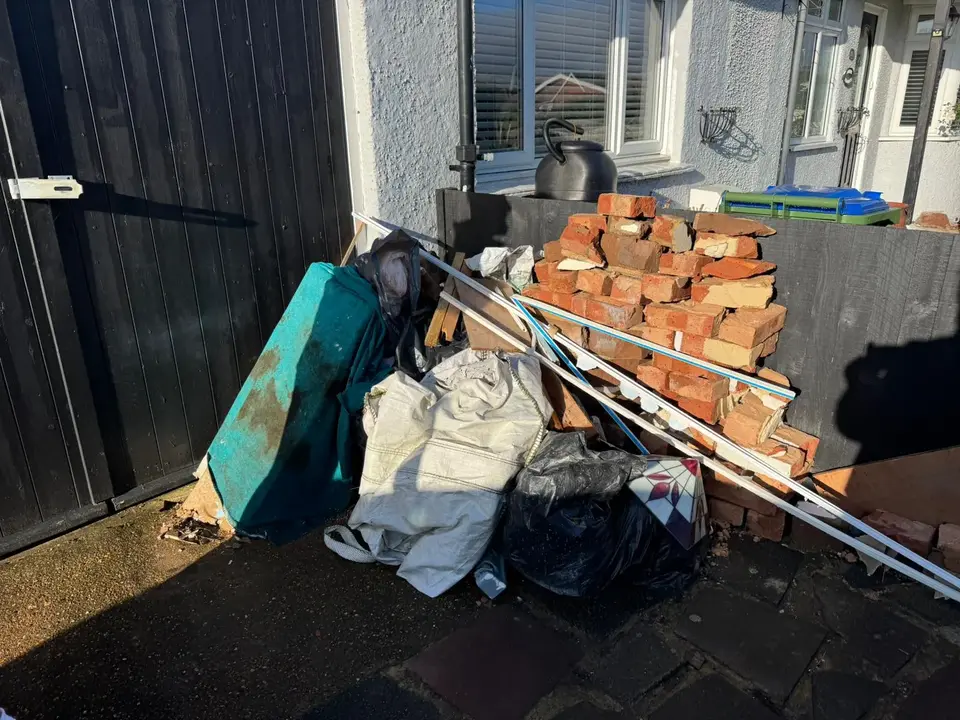Before: bricks, a mattress and bags stacked by a side gate