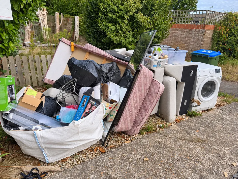 Before: a washing machine, bulk bag and mixed household waste on a gravel area