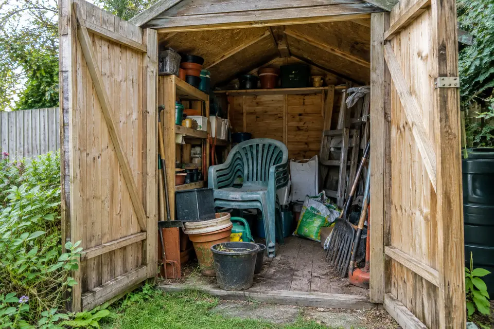 Garden shed full of pots, chairs and tools before being cleared