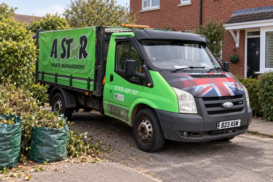 A Star van beside bags of cut branches and green waste in a front garden
