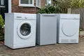 Washing machine, fridge and tumble dryer lined up on a driveway for collection